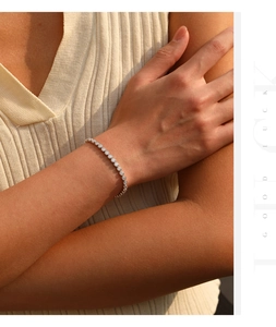 Detailopname van een zilveren tennisarmband met moissanite in bezelzetting om de pols