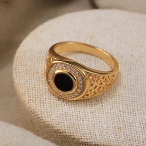 Close-up of gold ring with black gemstone and white zircon stones on filigree band