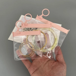 Hand holding three pink transparent EVA jewelry storage pouches in different sizes
