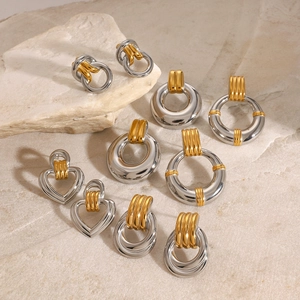 Two-tone mixed metal hoop earrings in gold and silver finish on natural stone background