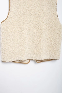 Close-up of off-white fleece vest with brown contrast piping and textured faux fur