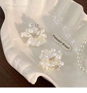 Dettaglio degli orecchini a fiore con perle su un vassoio a conchiglia in stile retrò francese