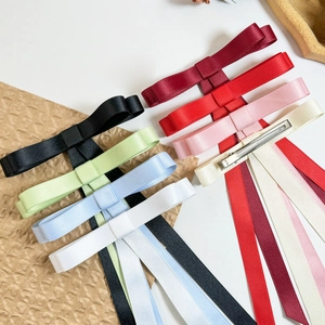 Flat lay detail of silky satin ribbon bow hair clips in eight different vibrant colors