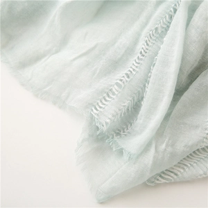 Detail of light mint green scarf showing breathable linen texture and tassel lace edges