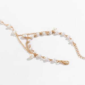 Detailed view of layered gold chain hand chain with white pearls and lobster clasp