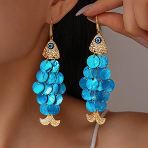Macro view of blue shell scale fish earrings with devil eye detail and golden finish