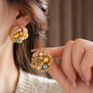 Gros plan de boucles d'oreilles vintage dorées avec perles, cristaux et roses en tissu