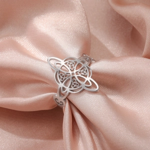 Detailed close-up of cutout Celtic knot silver steel ring on pink satin fabric