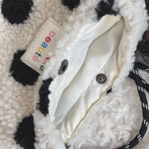Macro detail of plush polka dot storage bag with satin lining and metal snap closure