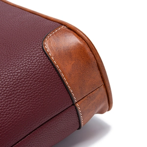 Close-up of pebble grain burgundy leather and brown smooth leather with white stitching