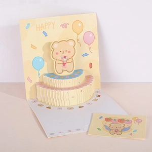 Detail of 3D pop-up birthday card with a cute yellow bear and tiered cake papercraft