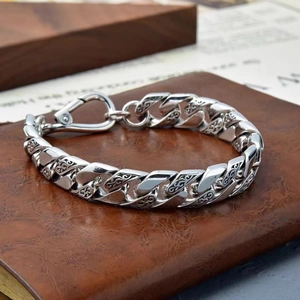 Bracelet pour homme en argent avec motif de vigne exposé sur un livre en cuir