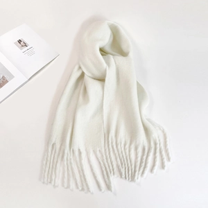 Solid white mohair scarf with tassels displayed on a white background with a magazine