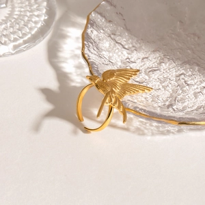 Detailed close-up of a golden dove bird ring perched on textured glass edge