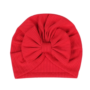 Close-up of red ribbed knit baby turban hat featuring a large decorative bow detail