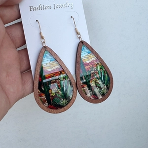 Macro view of teardrop wood earrings featuring colorful desert cactus print on white card