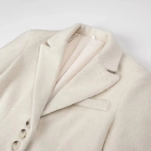 Detailopname van de revers en zachte pluche textuur op de crème imitatiebont jas