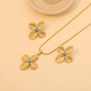 Elegant gold clover jewelry set with turquoise stones featuring necklace and stud earrings