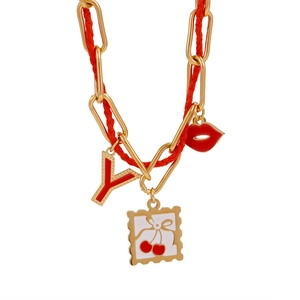 Detail of red cord necklace featuring gold charms with lip, cherry and letter Y pendant