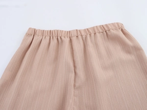 Gros plan du pantalon de vacances beige avec taille élastique et texture plissée verticale