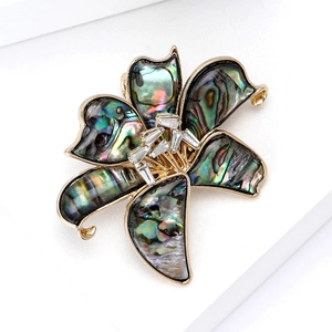 Elegant lily flower brooch with abalone shell petals and cubic zirconia on white background