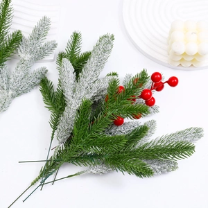 Artificial Christmas pine branch with red berries and faux snow on white background