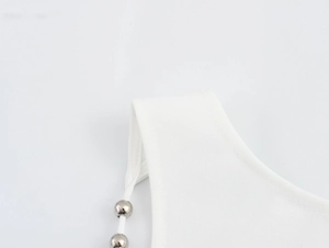 Close-up of white camisole strap with elegant silver bead accents on cotton fabric