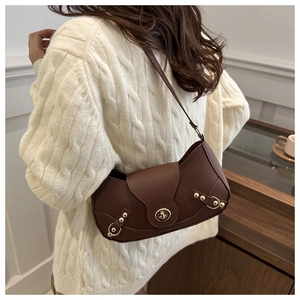 Detail view of a vintage dark brown crescent shoulder bag with gold clasp on a model