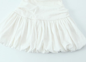 Close-up of white bubble hem dress featuring textured crinkle fabric and voluminous pleated detail