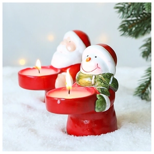 Close-up of Santa and Snowman ceramic candle holders with warm burning candles