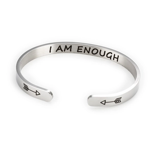 Detail view of silver stainless steel cuff bracelet with I AM ENOUGH engraving
