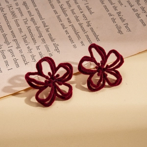 Gros plan de boucles d'oreilles fleurs floquées bordeaux avec texture velours doux