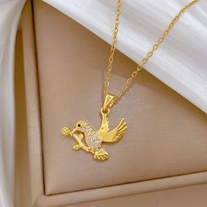 Macro shot of gold swallow pendant with sparkling crystals on warm silk texture