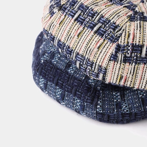 Close-up of contrast tweed beret fabric showing multi-color woven texture and detail