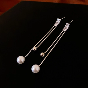 Detailed view of long tassel earrings with sparkling crystals and elegant white pearls