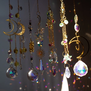 Macro view of crystal prisms and metal moon casting rainbow light spots on background