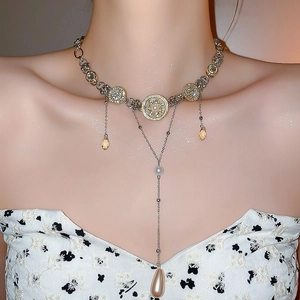 Detail of layered tassel necklace featuring vintage charms and amber teardrop pendants