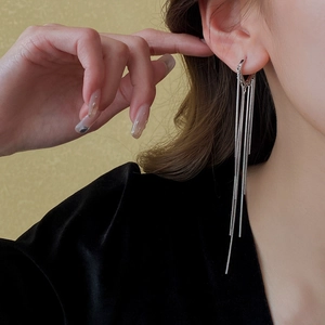 Détail des boucles d'oreilles longues à pampilles argentées portées pour un look luxe