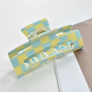 Detail of yellow and light blue checkered hair claw clip with a glossy finish on a book