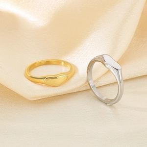 Polished gold and silver stainless steel heart rings on champagne satin fabric