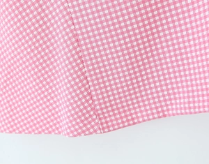 Close-up detail of pink and white checkered seersucker fabric texture and fine stitching