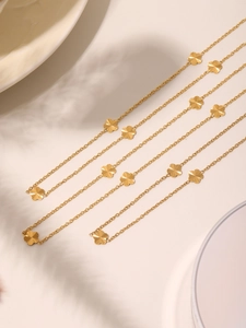 Detail shot of golden clover necklace with radial textured petals on a clean white background