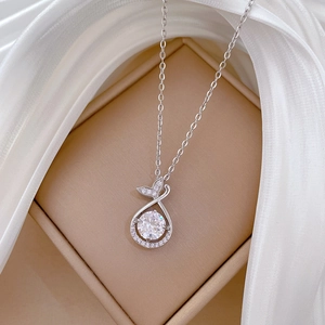 Macro shot of silver fishtail teardrop pendant with sparkling pavé diamonds on silk