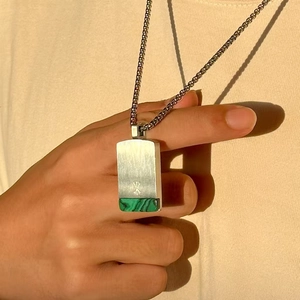 Malachite square stone pendant on a silver box chain shown in warm natural sunlight
