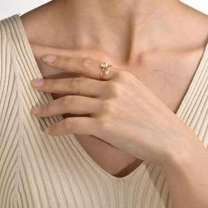 Detail of gold-plated open ring with double heart-shaped cubic zirconia on woman's hand