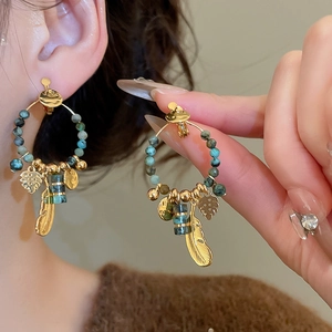 Detail of vintage bohemian feather and turquoise bead clip-on earrings in gold finish