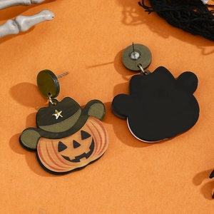 Halloween pumpkin earrings with cowboy hats on orange festive decorative background
