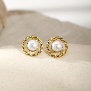 Macro detail of gold twisted rope border and white pearl stud earring on stone texture