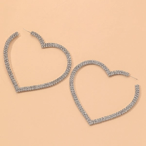 Gros plan de boucles d'oreilles créoles cœur argentées ornées de strass blancs brillants