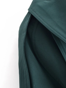 Detailed macro view of dark green trench coat showing twill fabric and premium stitching
